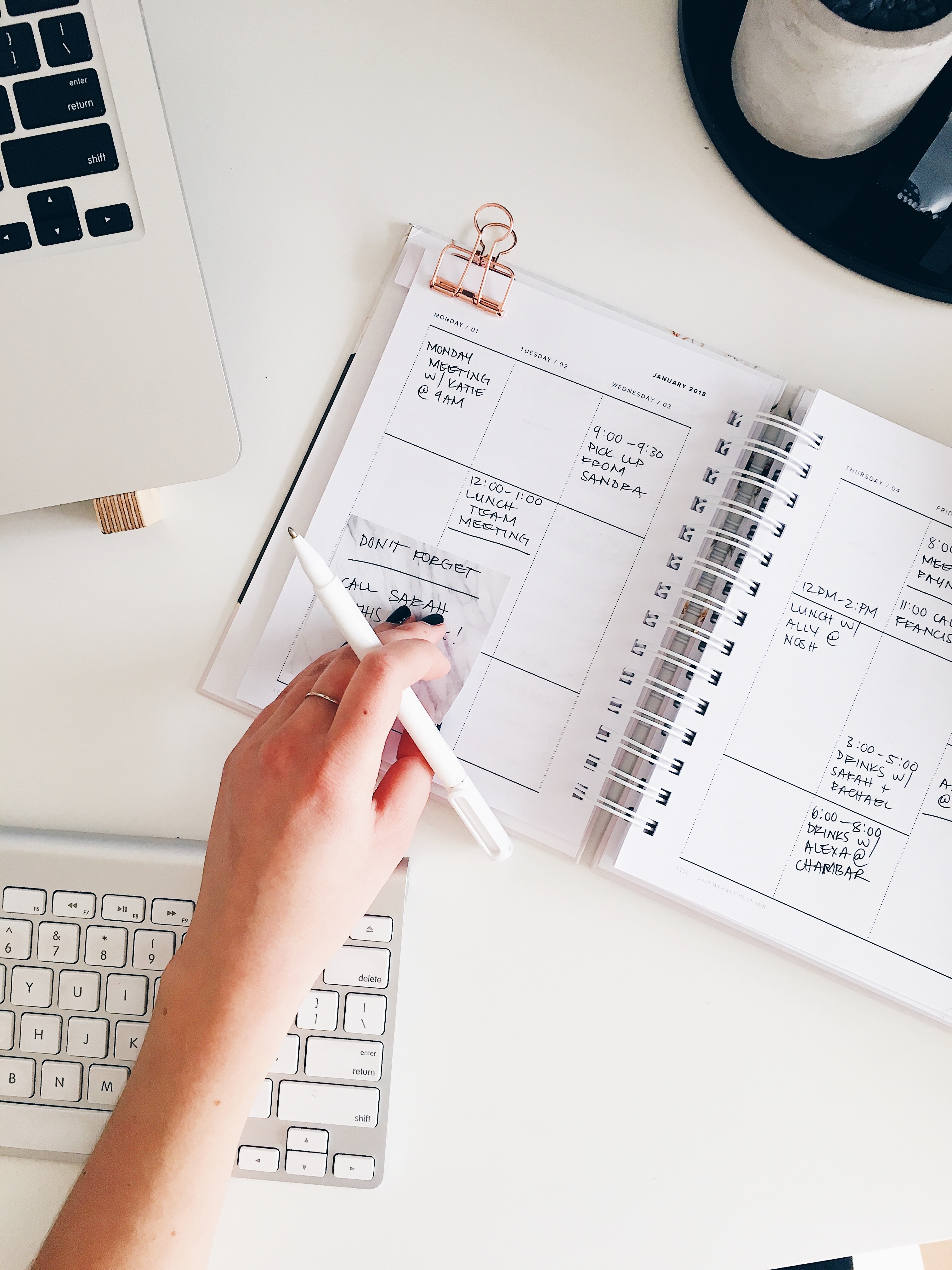 A person is writing in their planner with a pen