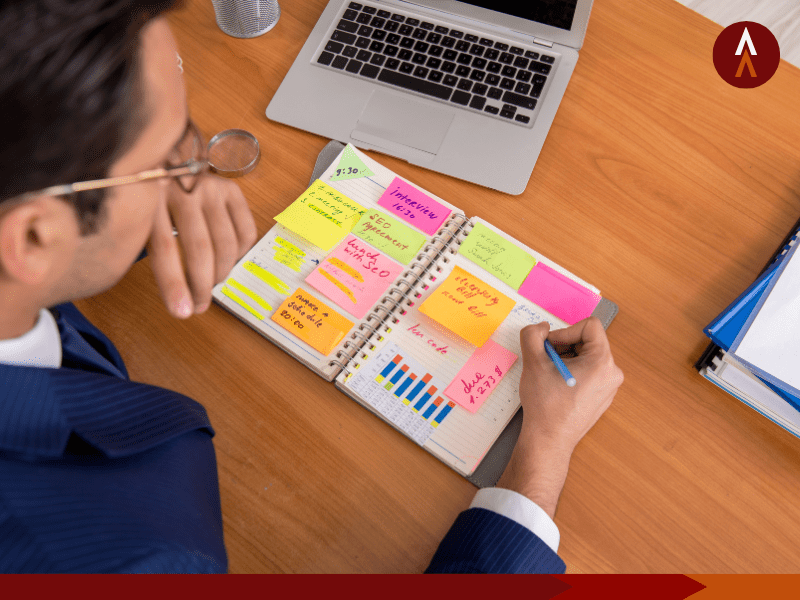 Person writing in a notebook filled with sticky notes